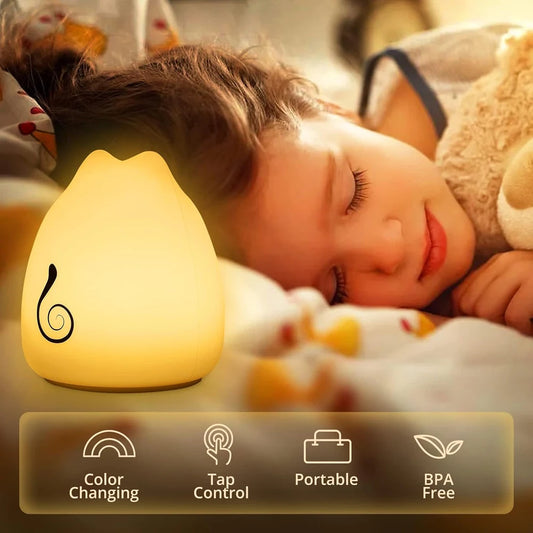 A child sleeps peacefully beside the Multicolor Cat-Shaped LED Night Light for Kids. The soft silicone lamp emits a warm glow, with icons below highlighting its features: color-changing, touch sensor control, portable design, and BPA-free. The child is snuggled in a cozy blanket.