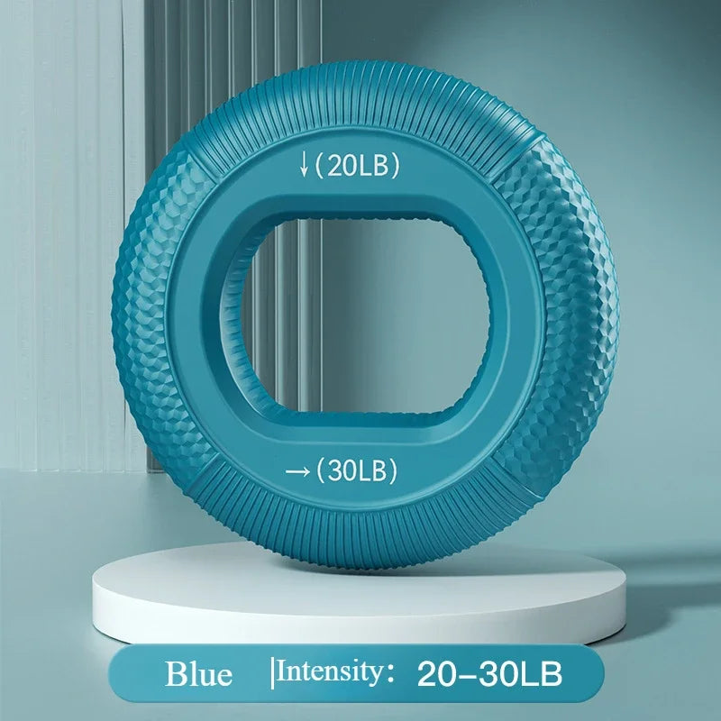 A blue Silicone Grip Trainer Ring for Hand Strengthening and Wrist Rehabilitation sits on a white cylindrical pedestal. It shows intensity levels from 20 to 30 pounds, set against a teal background with lines, enhancing its appeal for grip strength improvement.