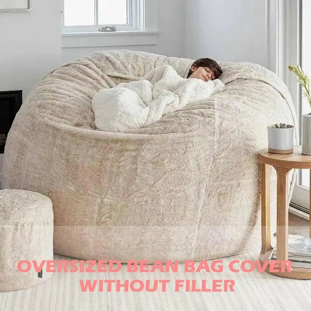 In a bright room with wooden floors, someone relaxes on a Giant 6FT Cozy Plush Bean Bag Chair for Adults and Families. Nearby is a small round seat, and a wooden side table with a potted plant. Text below states, OVERSIZED BEAN BAG COVER WITHOUT FILLER.