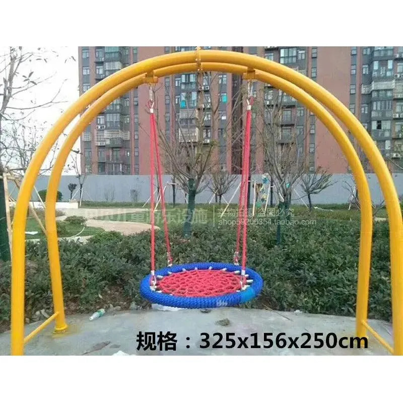 The Outdoor Steel Climbing Frame Swing, designed for childrens sensory integration training, features a round netted swing on a yellow arch-shaped frame supported by red ropes. An apartment and bare trees form the backdrop. Dimensions are 325x156x250 cm.