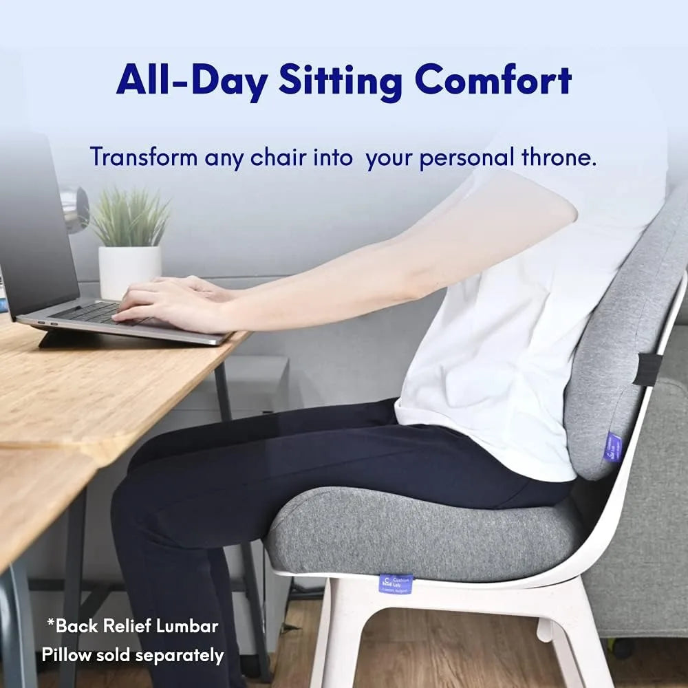 Seated on the Cushion Lab Patented Pressure Relief Seat Cushion, a person works on a laptop in a serene setting with a plant and desk. All-Day Sitting Comfort highlights the cushions supportive design for long hours on office/home chairs, cars, or wheelchairs.