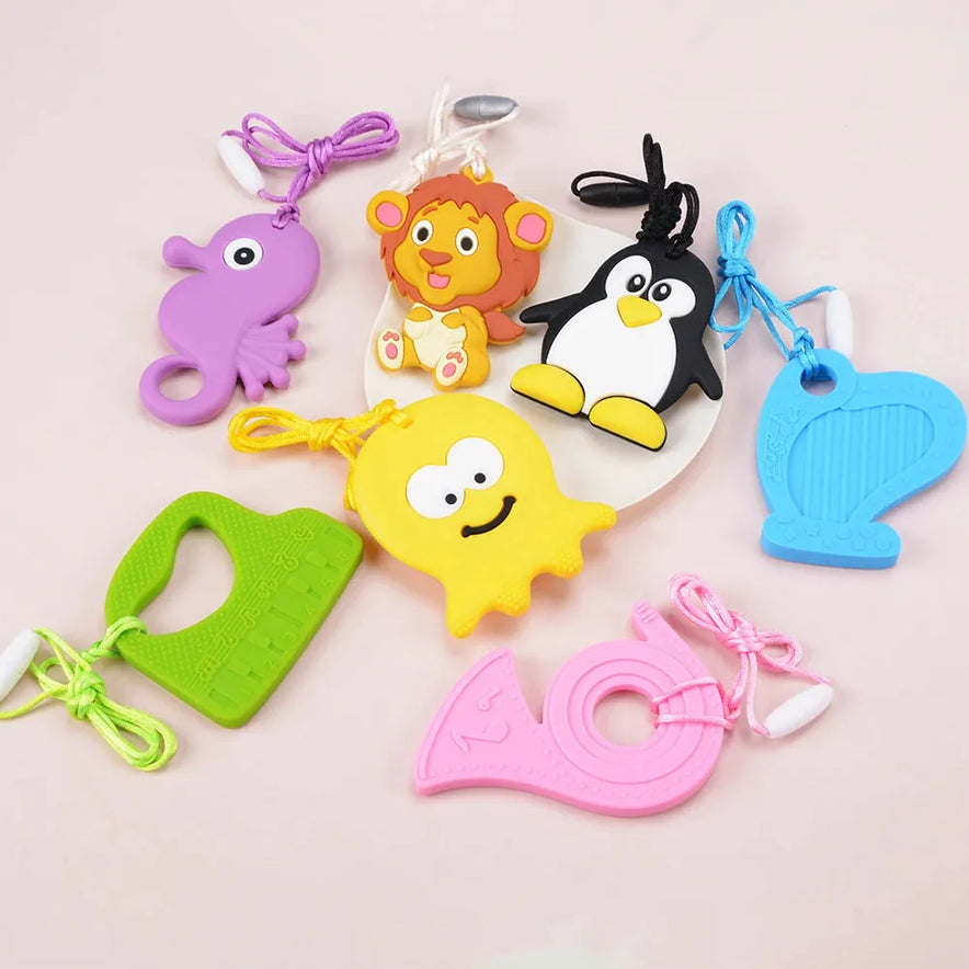 A set of colorful silicone chewable necklaces, perfect for sensory teething therapy, shaped like various animals and objects, including a lion, penguin, octopus, a green mitten-shaped pendant, a pink tape measure, and a blue harp. Each design features an easy-holding loop.
