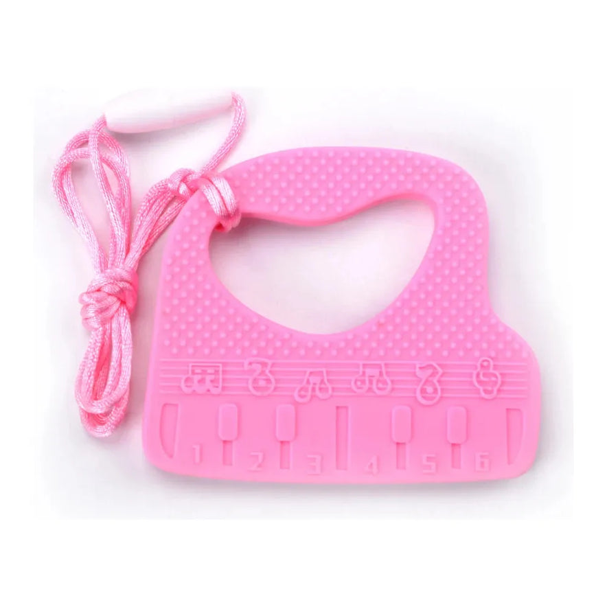 The Silicone Chewable Necklace for Kids, shaped like a piano, is pink with textured dots and embossed musical notes (1-6). Ideal for autism and ADHD therapy, it features a pink and white cord.