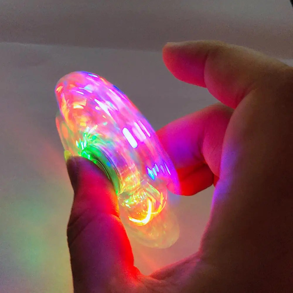 A hand holds a Crystal Finger Spinner Luminous LED Light Fidget Spinner, creating a glowing pattern in the dark. This captivating display offers both visual delight and stress relief.