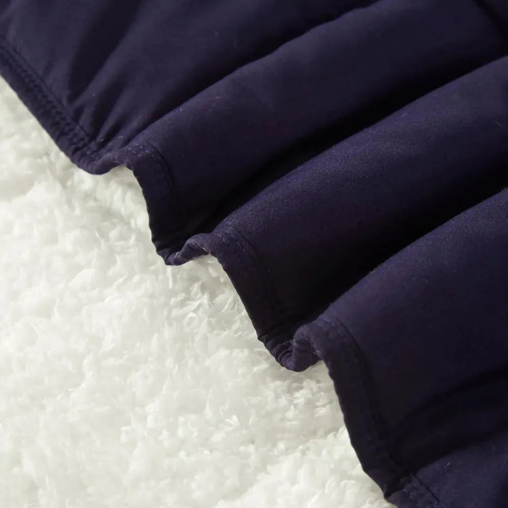 Close-up of a navy blue quilted fabric on a white textured surface, highlighting the stitching and contrast in colors and textures of the Luxurious Microfiber Weighted Blanket, a super soft plush bedspread for sofa and bed with free delivery.
