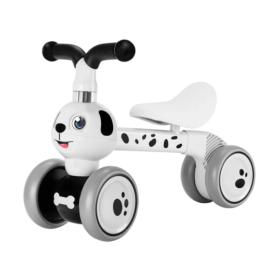 The Spotty Dog Baby Balance Bike with 4 wheels is a white and black ride-on for toddlers ages 12-36 months, featuring a cute dog design. It makes an ideal first birthday gift and helps develop gross motor skills with its stable seat and handlebars.