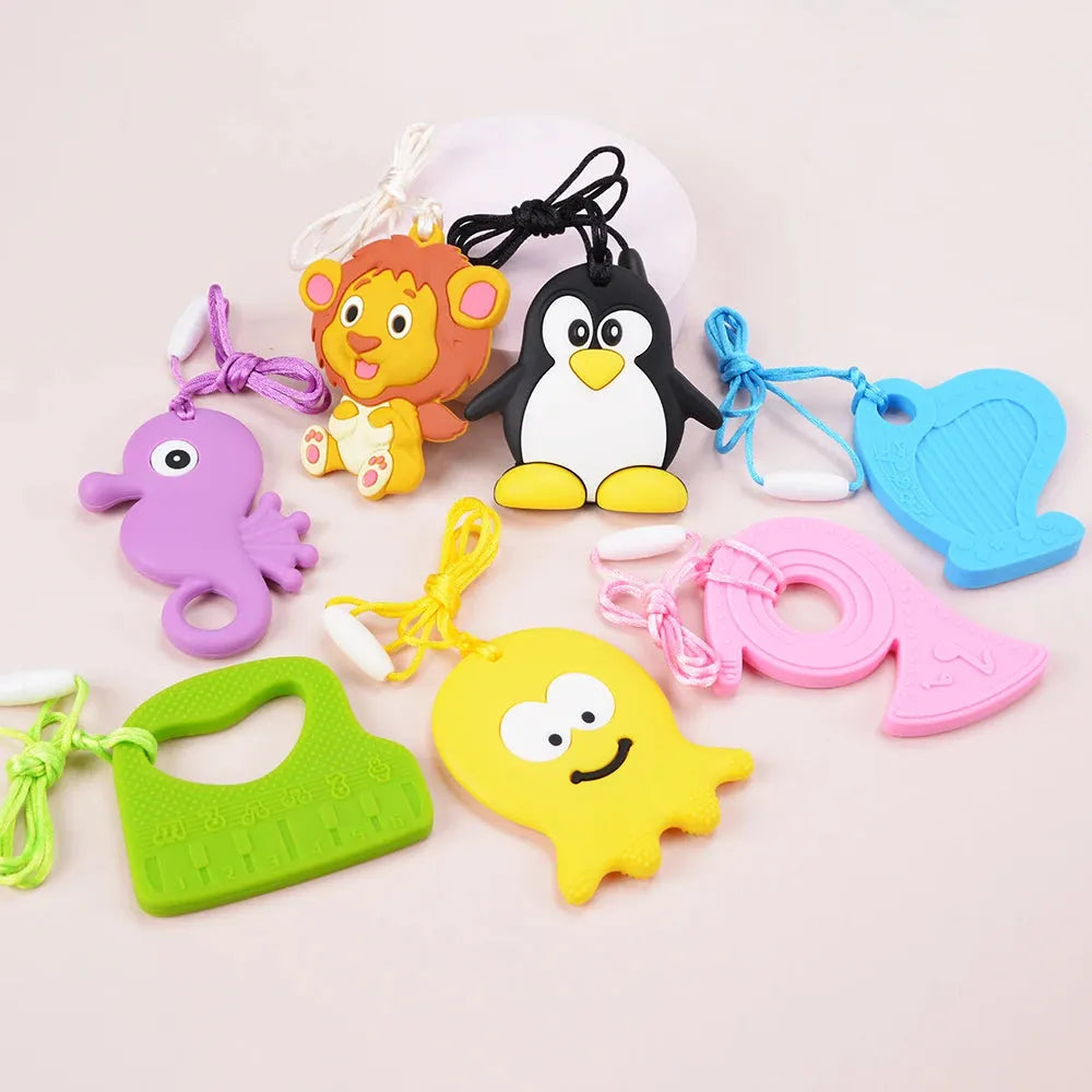 The Silicone Chewable Necklace for Kids, ideal for autism and ADHD therapy, features colorful teething toys with vibrant shapes like a lion, penguin, and seahorse. Each pendant includes a loop to attach to a string or clip, perfect as chew necklaces displayed elegantly on a light surface.