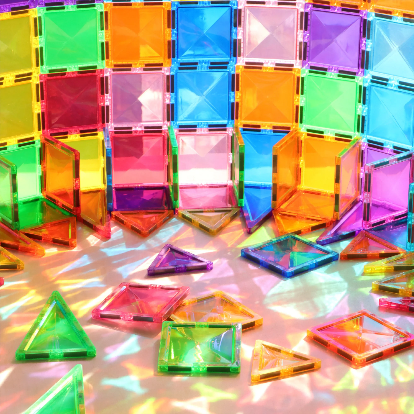 A set of Montessori Magnetic Building Blocks forms a curved wall and scatters on the ground, with sunlight casting vibrant, multicolored shadows for an interactive learning experience.