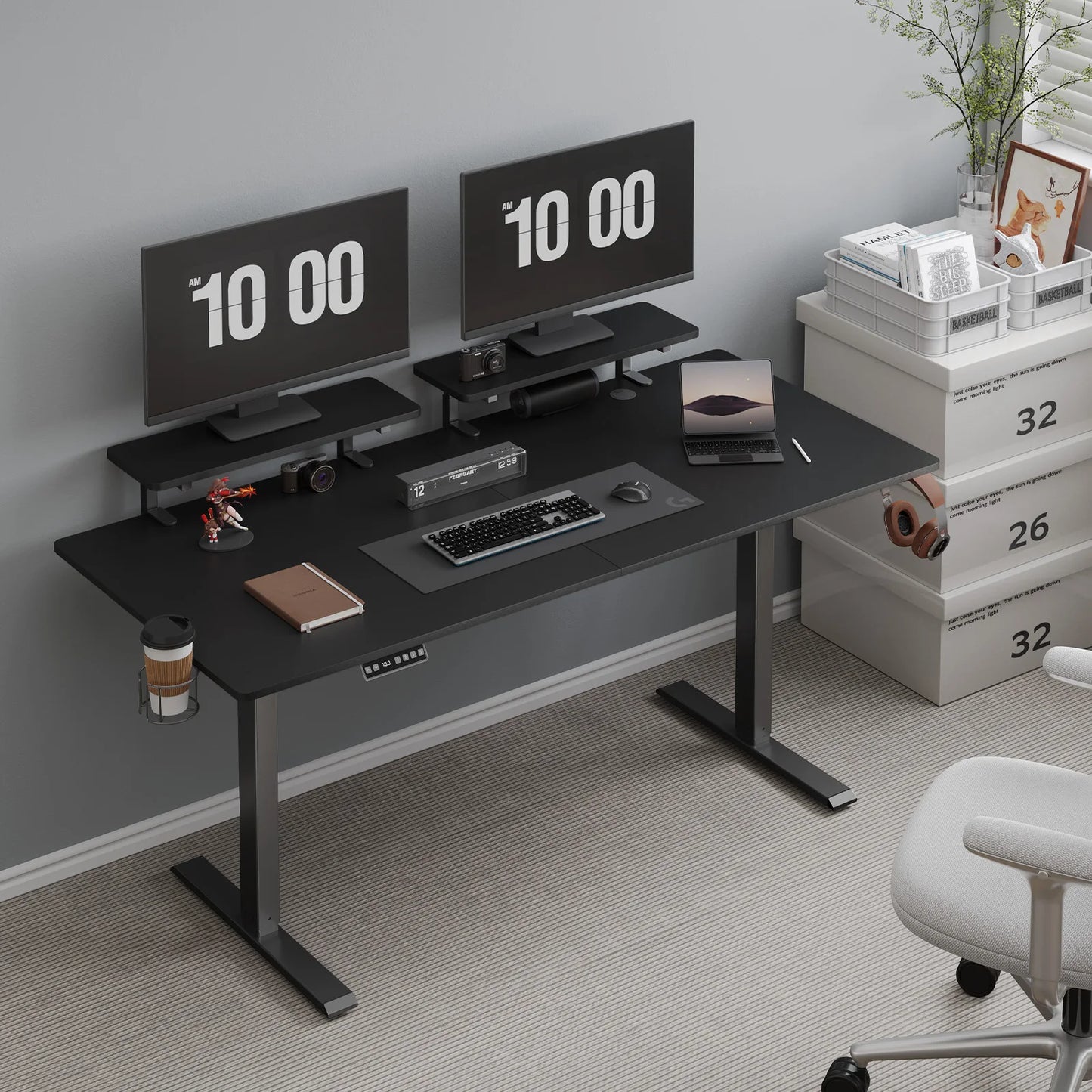 Minimalist home office featuring the 55-inch Black Standing Desk w/ 2 Adjustable Monitor Shelves Electric Stand Up Desk, dual monitors displaying 10:00, keyboard, mouse, laptop, headphones, books, a cup, white drawers and a white chair on carpet.
