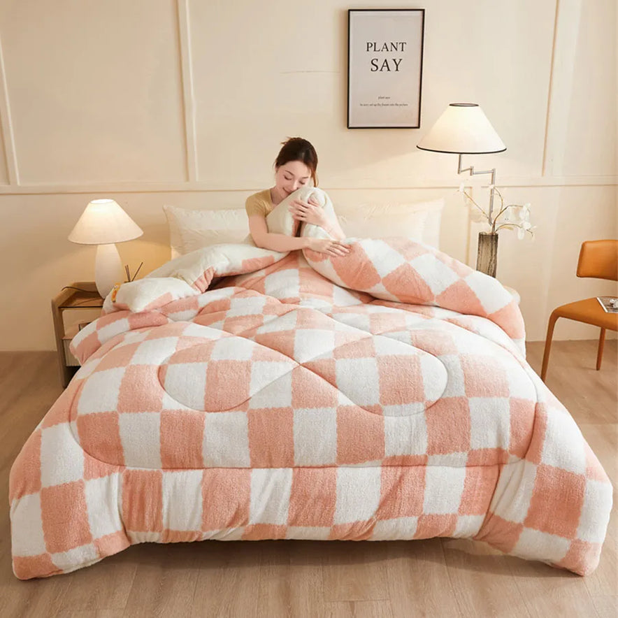 A person sits on a bed with the KDJEIKZ Ultra Cozy Winter Weighted Blanket, featuring a fluffy pink and white checkered pattern. The room includes a lamp, framed quote, small table with a plant, and chair. The weighted design of the luxurious milk velvet creates a cozy ambiance.
