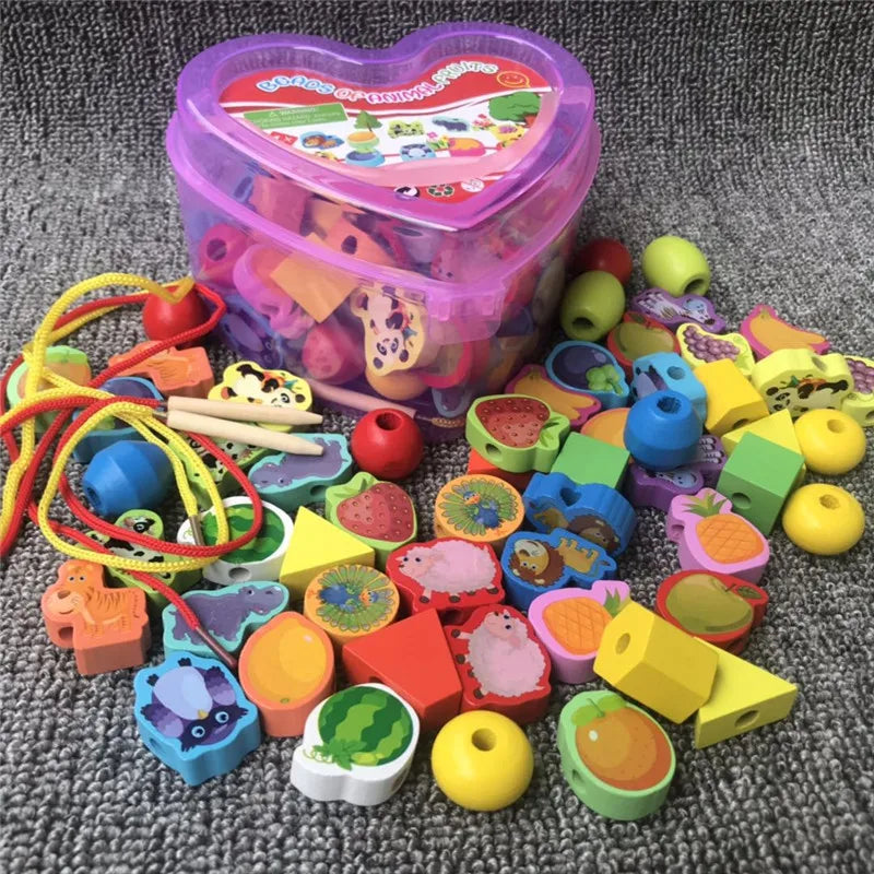 A 50-piece set of baby wooden lacing beads features vibrant animal shapes on a grey carpet. A heart-shaped plastic box nearby, with strings for threading, promotes educational play and fine motor skill enhancement.