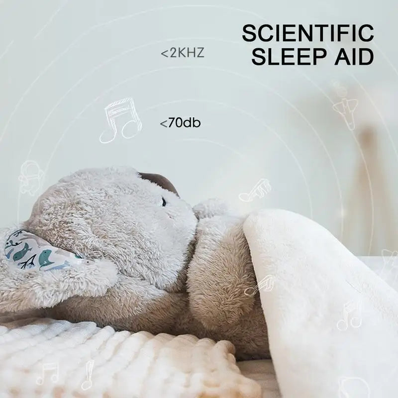 A Koala Night Light Plush Toy sits on a bed under a white blanket with musical notes and waves. It features <2KHz, <70db, and Scientific Sleep Aid text, offering soothing melodies for restful sleep as a Musical Sensory Sleep Aid for Newborns.