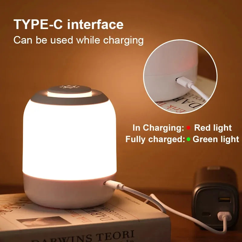 The Touch Control LED Night Light Lamp, with a Type-C USB interface, lights up red when charging and green when fully charged. It is resting on a book while the charger is plugged in the background.