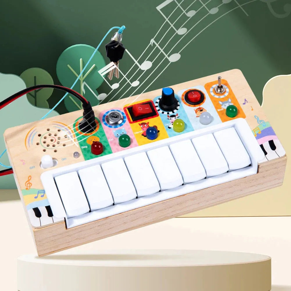 The Multifunctional LED Piano Busy Board for Toddlers features a vibrant wooden design with eight white keys, playful buttons, switches, and knobs to enhance fine motor skills. Lively musical notes and designs adorn the surface, and a wire with a clip extends from the top left.