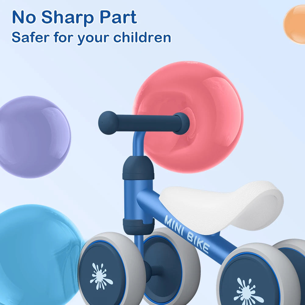 The Baby Balance Bike Ride On Toy for 1 Year Old Boys and Girls is shown with rounded edges and no sharp parts against a background of colorful spheres. Text reads: No Sharp Part—Safer for your children. Great for gross motor skills development!.
