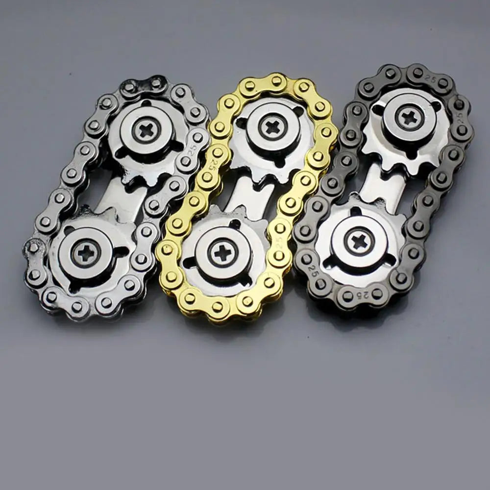 Three Sprockets Flywheel Fingertip Gyro Fidget Spinners by MezoJaoie, ideal for dropshipping, are side by side with intricate bike chain designs; one is silver, another is gold, and the third has dark accents on a plain gray background.