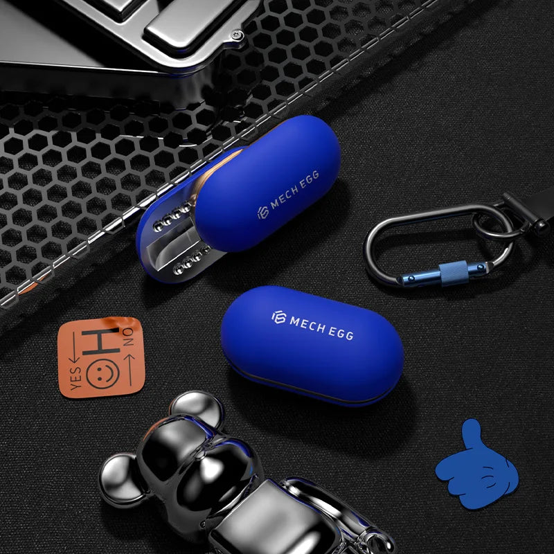 A pair of blue Mech Egg EDC Fidget Sliders, one open and one closed, rest on a black surface with a keychain, metal bear figurine, phone, and YES/NO token—ideal as an ADHD stress relief toy for adults in the office or at home.