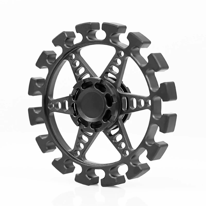 The black, circular object with a gear-like design resembles the Bike Chain Metal Fidget Spinner with a Magnetic Slider. It has radial arms connecting to an outer ring and is set against a white background, making it perfect for stress relief.