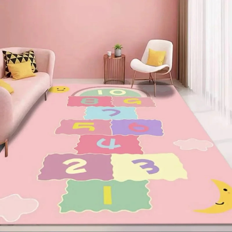 A pastel pink playroom with the MINISO Cartoon Hopscotch Carpet Non-Slip Mat featuring colorful numbered squares, a pink sofa with patterned pillows, a modern white chair, side table, and sheer curtains letting in light.