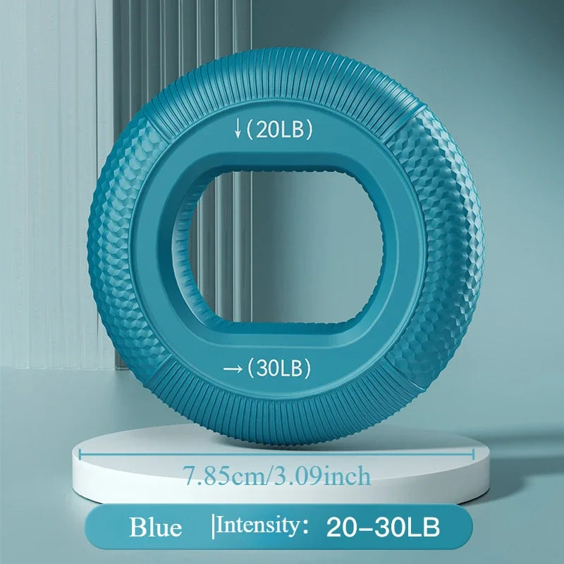 A textured blue Silicone Grip Trainer Ring for hand strengthening stands on a white round platform. With a 20-30 lbs weight intensity and measuring 7.85 cm (3.09 inches) in diameter, its sleek design is showcased against a soft teal backdrop, perfect for grip strength training.
