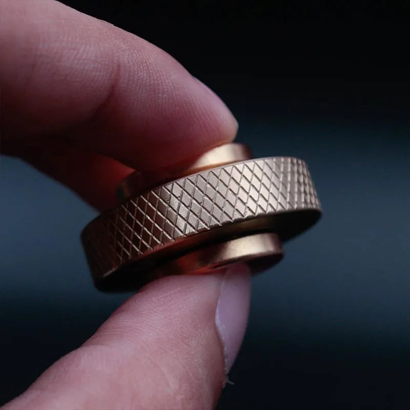 Close-up of a hand holding the Creative Whirlwind Fidget Spinner, a bronze-colored ring with a grid-like texture. Its innovative design and intricate details stand out against the blurred background, making it an ideal stress relief tool for both kids and adults.