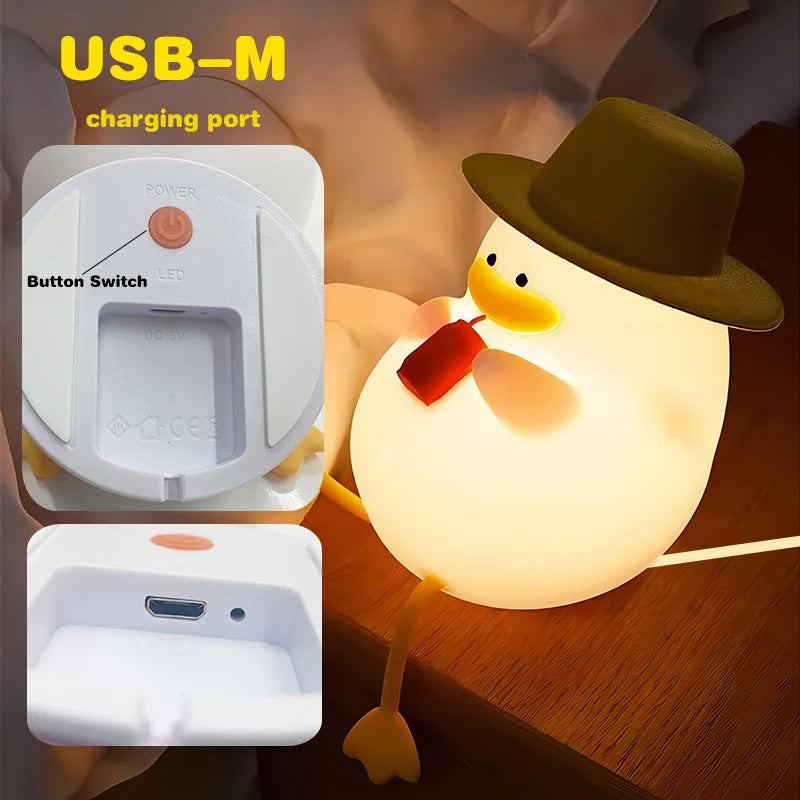 The Cute Cartoon Duck Rechargeable LED Night Light is a silicone lamp shaped like a duck with a hat, holding a red object. It features a USB-M charging port and button switch. Ideal for kids room decor, it adds charm and is the perfect birthday gift.