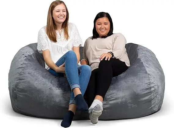 Two women sit and smile together on the Fuf XXL Foam Filled Bean Bag Chair in grey, 6 feet long, against a white background.