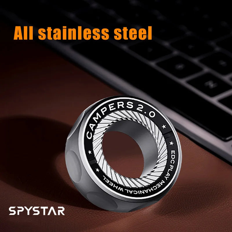 A silver Spystar Mechanic Ring Fidget Spinner Fingertip Gyro Ratchet Magnetic Metal Adult Anti Stress Toy (Silver-A 2) rests near a keyboard on a dark surface. All stainless steel text is above; the SPYSTAR logo appears at the lower left.