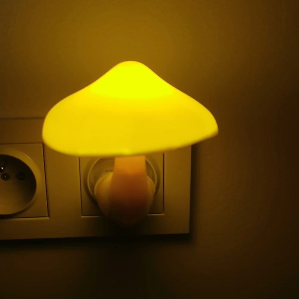 The Mushroom LED Night Light with Sensor Control emits a warm white glow when plugged into a wall socket, creating a cozy ambiance in the dimly lit room.