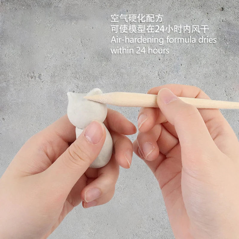 Hands sculpting a small figure using a wooden tool on a gray background. Text above reads, No-bake Air-dried Shaping DIY Plasticine Clay Set dries within 24 hours in English and Chinese, ideal for educational pottery projects with 12 paint colors.