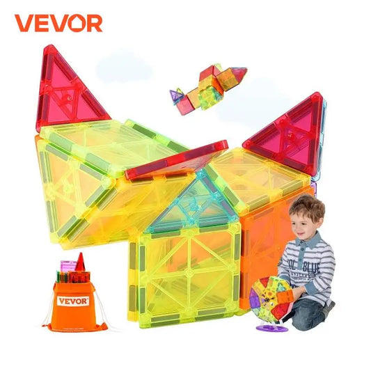 A child uses the VEVOR 180PCS Magnetic Tile Building Set, an educational toy, to build colorful geometric shapes, creating a large structure with two red triangular peaks. Nearby are a small cube and bird figure. A container labeled Vevor is also visible.