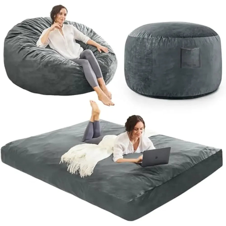 A woman relaxes on a Queen-Charcoal Bean Bag Chairs Convertible Bean Bag Bed made of soft microfiber, which converts from chair to ottoman or a flat bed. She uses a laptop with a blanket placed beside her.