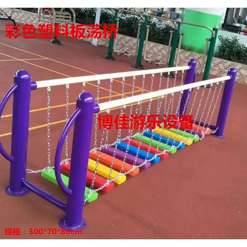 A vibrant playground set, similar to unisex toys, includes a swinging bridge made from multicolored planks and chain links. The structure has purple support posts and sits on a red rubber surface. It features colored plastic boar components and serves as sports equipment for physical training.