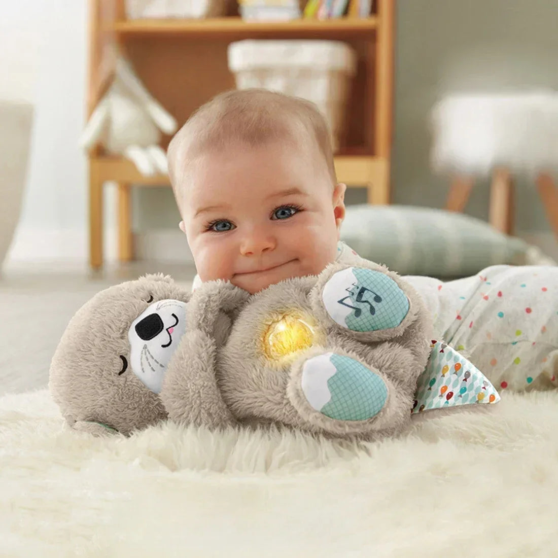 A baby lies on a soft, light rug, smiling while holding the Soothing Breathing Otter Musical Plush Toy with Light and Sound for Newborns. Its chest glows gently in the softly lit room, complemented by wooden furniture, ensuring perfect newborn comfort.