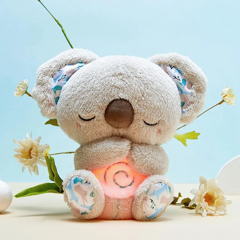 The Koala Night Light Plush Toy: Musical Sensory Sleep Aid for Newborns features a cute stuffed koala with eyes closed and patterned ears and paws, surrounded by flowers. Its softly glowing belly acts as a pink night light, creating a serene ambiance against the pastel blue background.