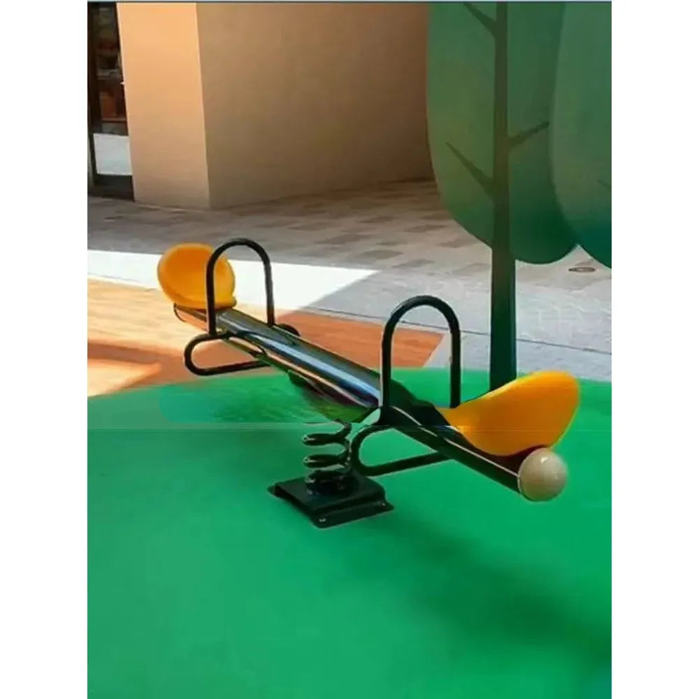 An Outdoor Steel Climbing Frame Swing with yellow seats and black metal handles sits on a green surface, boosting childrens sensory integration. The backdrop shows a tree design and building wall for an engaging setting with diverse outdoor play equipment.