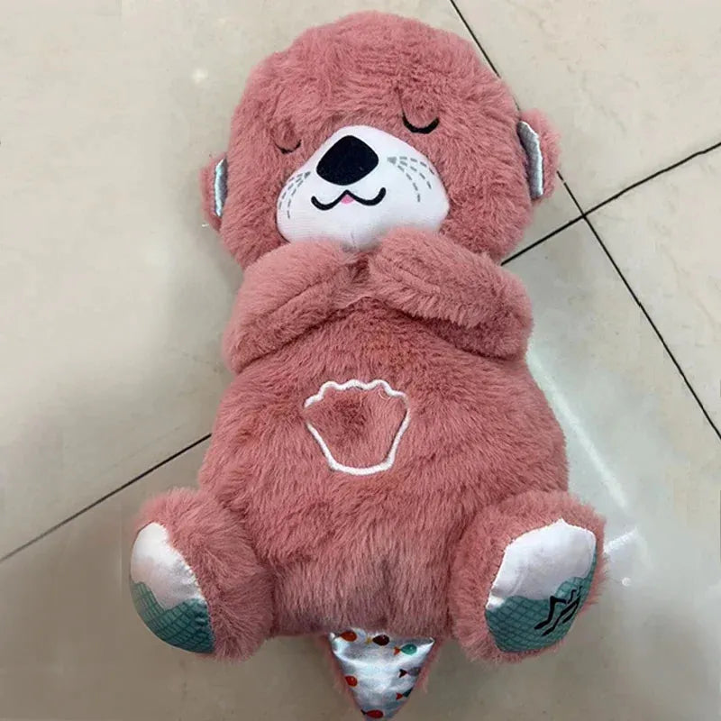 A pink plush teddy bear, designed for babies with closed eyes, a white muzzle, and embroidered paw prints on its belly and feet, lies cozy on a tiled floor.