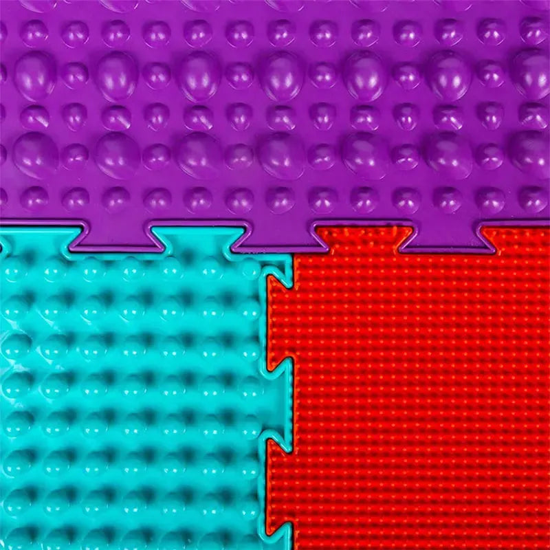 Close-up of three interlocking Montessori Sensory Integration Training Balance Stones for Kids: the top is purple with raised bumps, bottom left teal with similar bumps, and bottom right red with a grid texture. Ideal educational toys, these mats fit together like puzzle pieces.