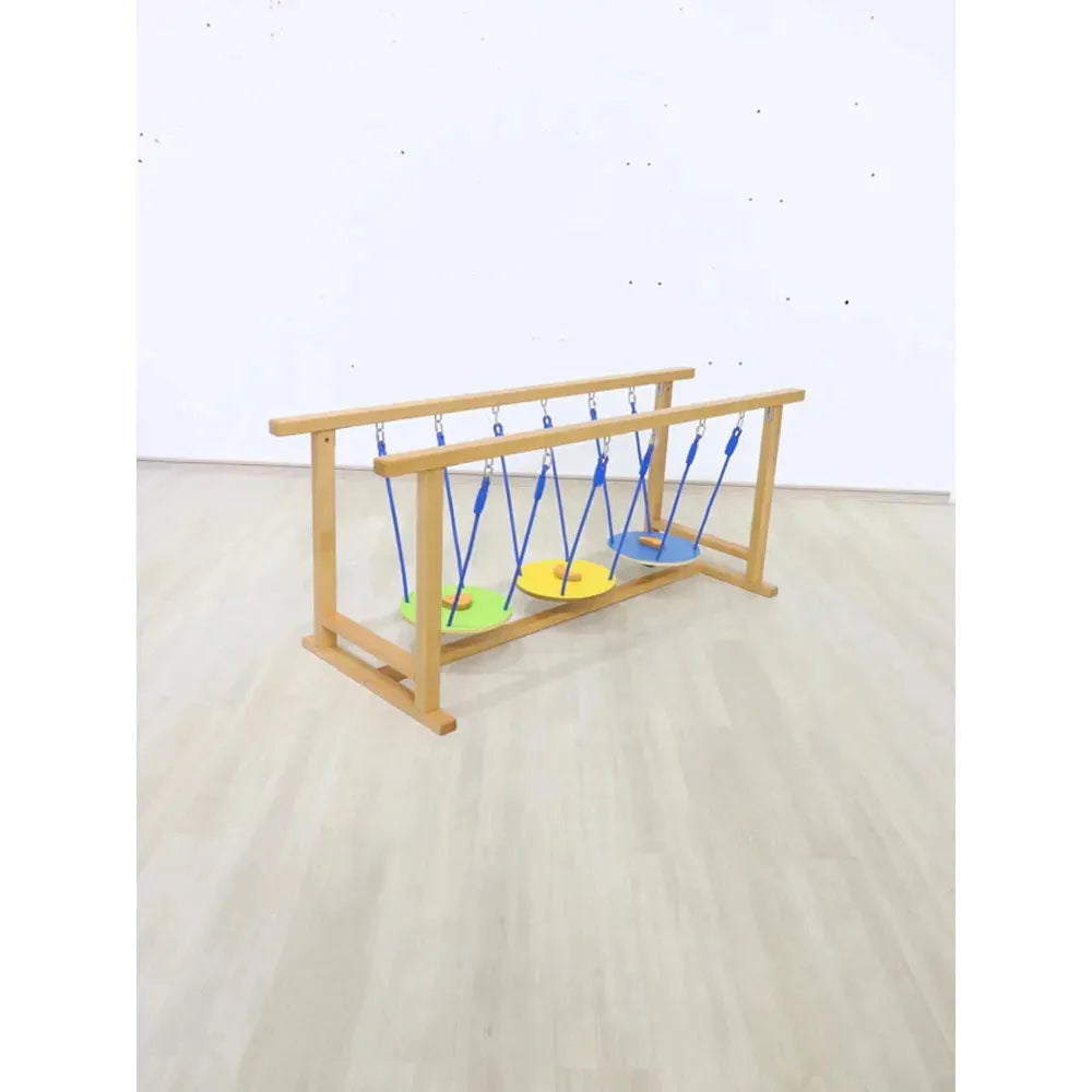 The Indoor Wooden Balance Beam Sensory Training Toy for Children ages 3-12 features three colorful circular platforms suspended by blue ropes, perfect for indoor balance activities. Its set on a light wood floor against a plain white wall, ideal for sensory system training.