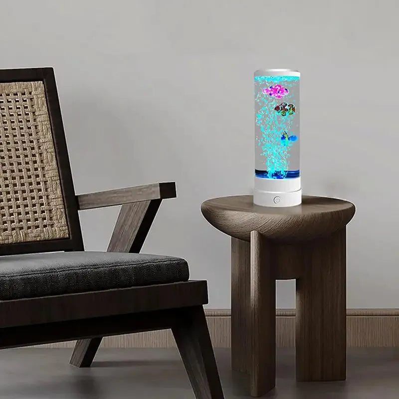 An Enchanting Bubble Fish Night Light Aquarium Lamp featuring glowing blue water and color-changing effects illuminates a small wooden table next to a woven-backrest chair in a room with light gray walls and wooden flooring, creating an authentic aquarium ambiance.