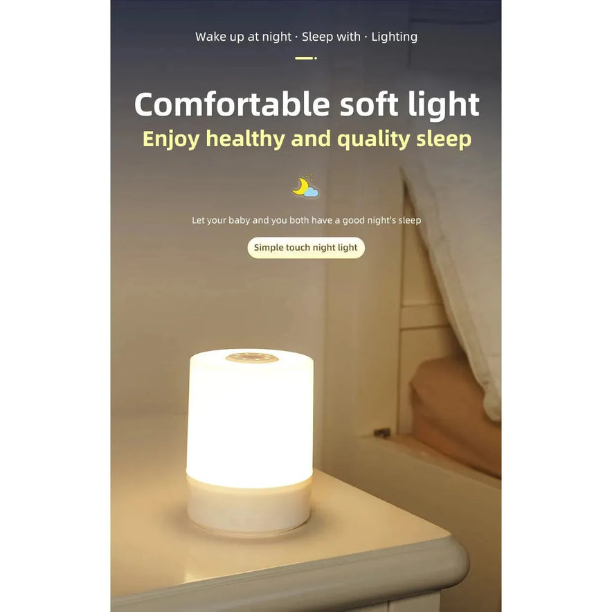 A Rechargeable Dimmable Touch LED Night Light USB table lamp, featuring a soft glow and crescent moon icon, sits on a bedside. Text reads Comfortable soft light: Enjoy healthy and quality sleep with a cozy bed and pillows in the background. Perfect Christmas gift for kids.