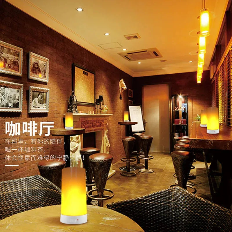A cozy coffee shop with warm lighting and brick walls features wooden tables and high stools. Simulated Flame LED Night Lights create an inviting atmosphere. Framed pictures adorn the walls, and elegant decor enhances the rustic charm for versatile usage.