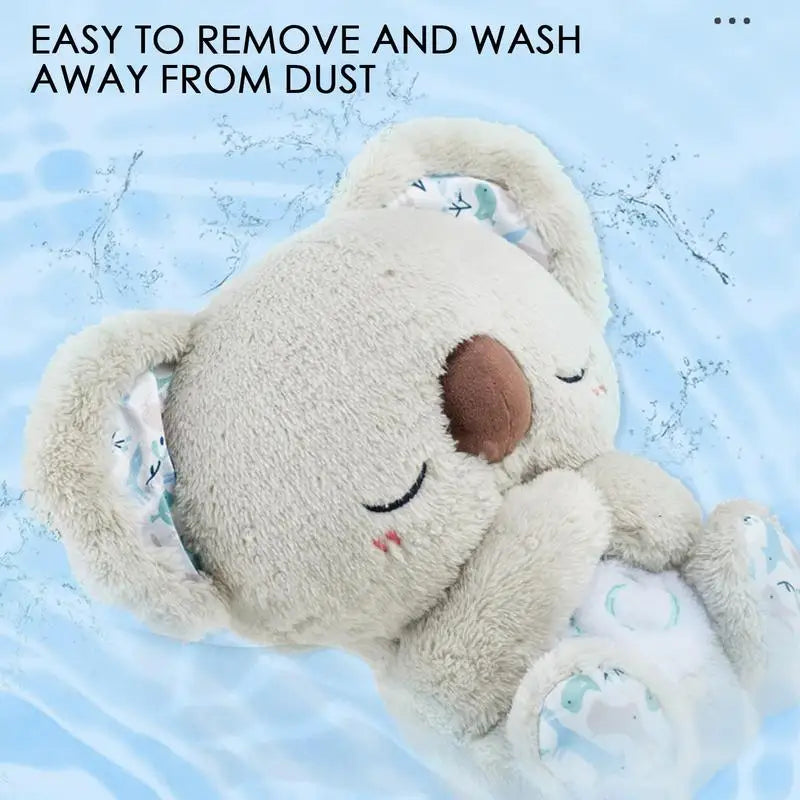 A koala night light plush toy with closed eyes floats in water, playing soothing melodies. Text reads Easy to remove and wash away from dust. Its ears and feet have a pattern with small animals and stars against a clear blue background resembling water.