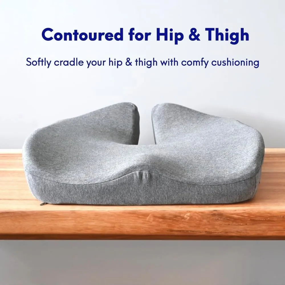 A gray U-shaped memory foam cushion lies on a wooden surface. Above reads: Contoured for Hip & Thigh; below: Softly cradle your hip & thigh with comfy cushioning. Product: Cushion Lab Pressure Relief Seat Cushion for Long Sitting Hours on Office/Home Chair, Car, Wheelchair.