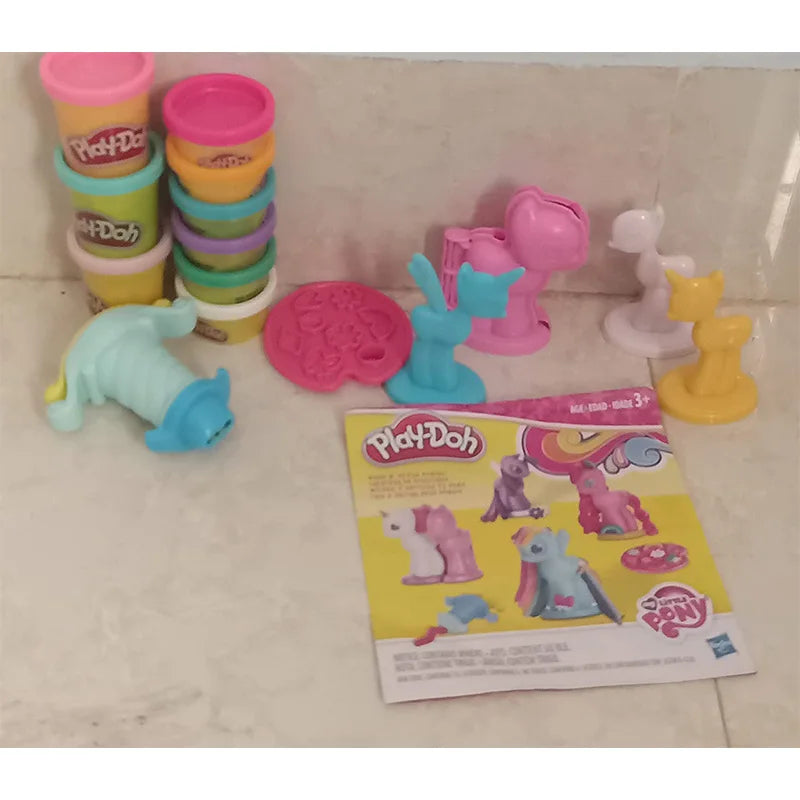 The My Little Pony Play-Doh Modeling Compound set showcases vibrant dough tubs on the left and pastel unicorn molds on the right. In front, a detailed instructional booklet reflects the meticulous craftsmanship found in TAKARA TOMY products.