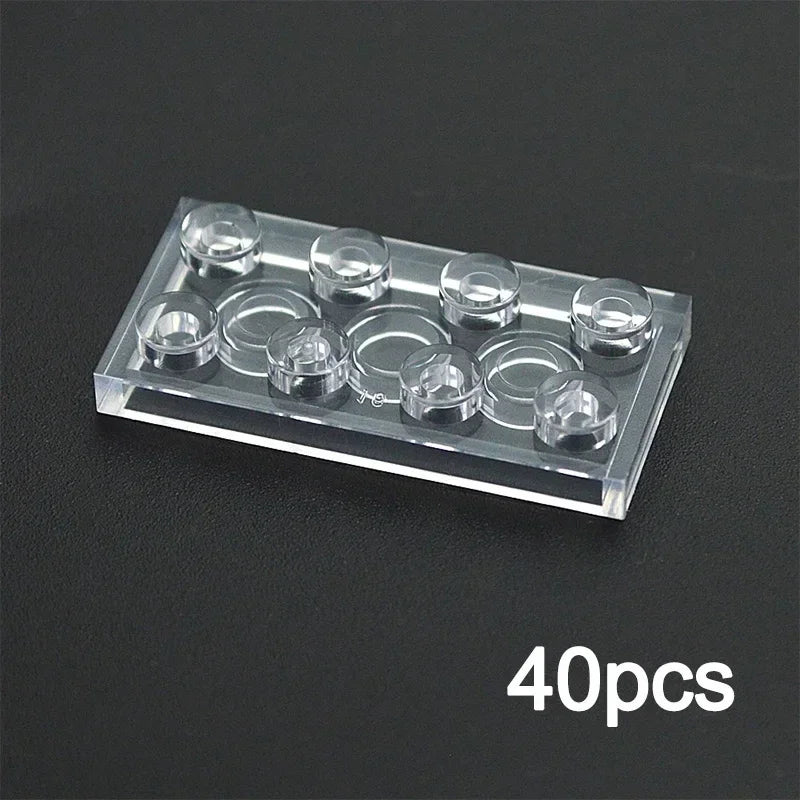 A transparent 2x4 building block, compatible with Lego and part of the MOC Transparent Bulk Brick Set, sits on a dark surface. 40pcs in the corner highlights this clear brick from the 1x1 1x2 1x4 2x4 collection.
