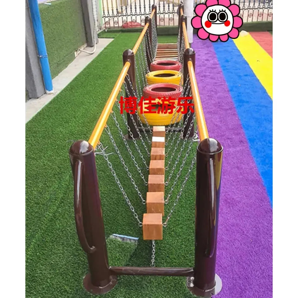 The childrens playground equipment includes swinging bridges with wooden planks and chain supports for ages 3-8, colorful tire stacks, a unisex design on a multicolored floor with artificial grass, plus a cartoon flower decor. Its part of outdoor toys like swings and climbing nets for sensory integration.