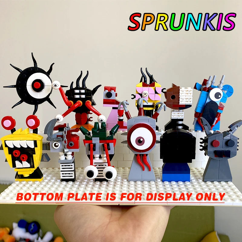 A hand holds a gold display plate with ten unique LEGO creatures from the New Moc Incredibox Sprunki Building Blocks Set. SPRUNKIS appears in rainbow text above; BOTTOM PLATE IS FOR DISPLAY ONLY is written in red at the bottom.