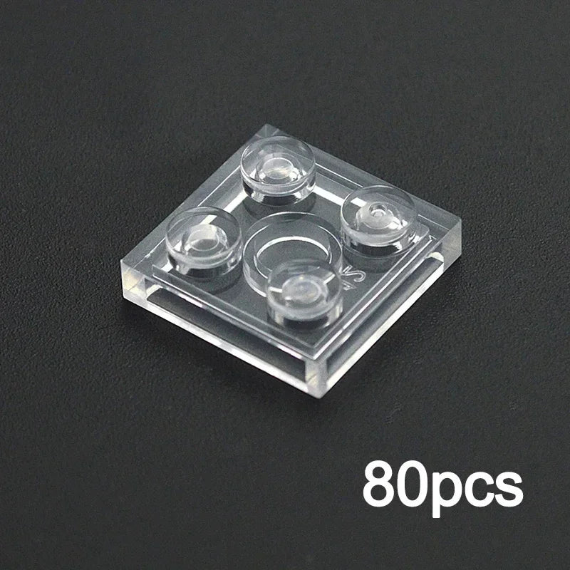 A transparent 2x2 brick compatible with Lego from the MOC Transparent Bulk Brick Set sits on a black surface. The lower right corner shows “80pcs,” indicating the quantity included in this clear building block set.