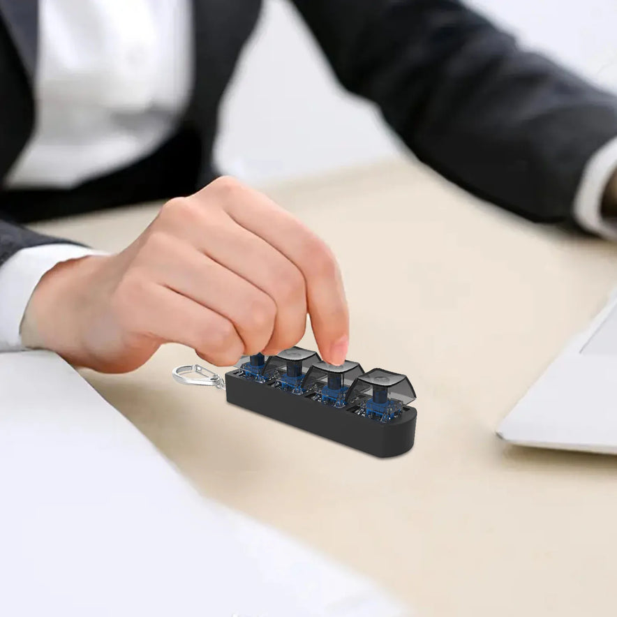 A person in business attire presses a key on the 4Keys Finger Button Anti Stress Toys Mechanical Keyboard Keycaps, placed on a light-colored desk next to a laptop.